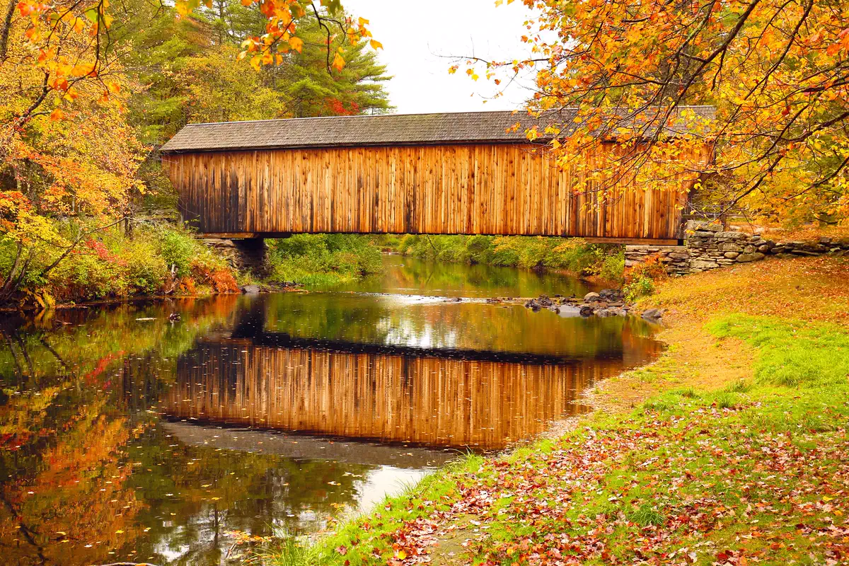 Covered bridge reflected in water during a New Hampshire autumn