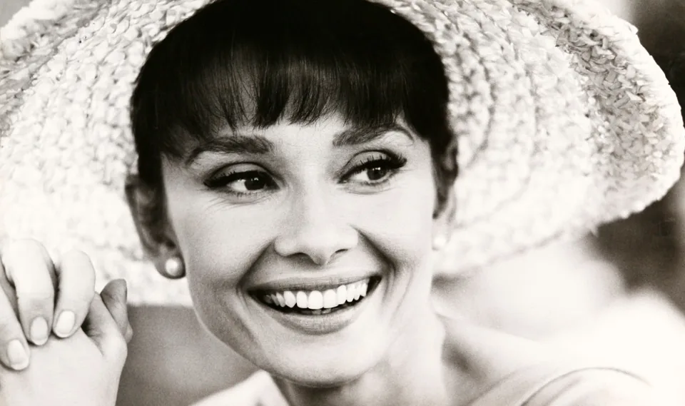 Black-and-white portrait of a smiling woman wearing a hat