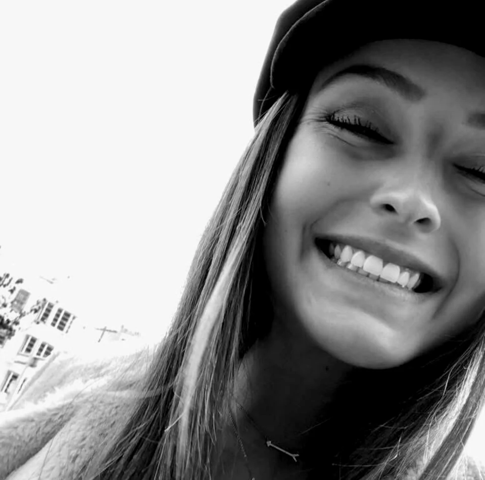Black-and-white close-up of a smiling woman wearing a cap