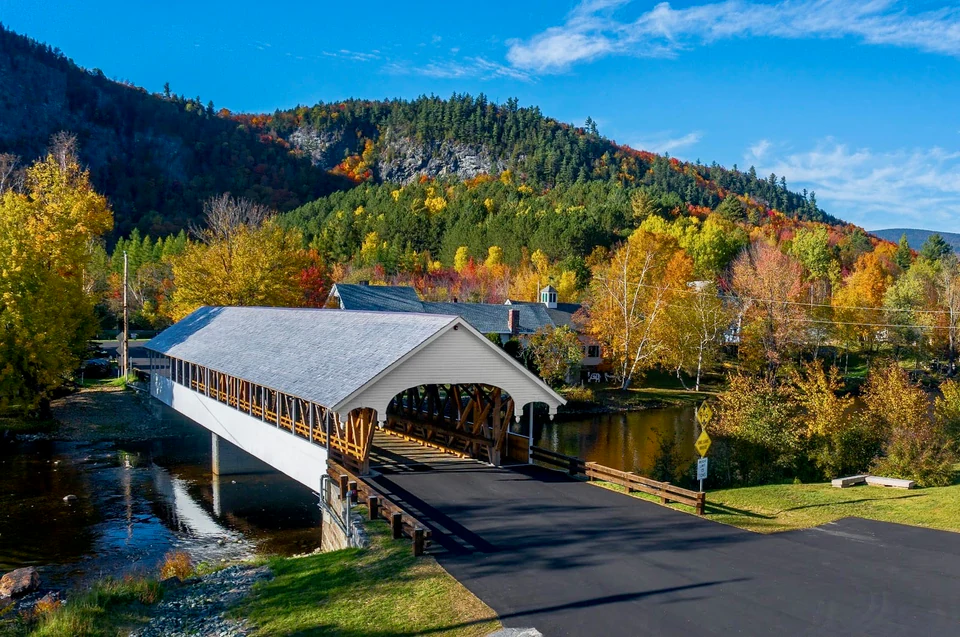 White covered bridge surrounded by autumn trees